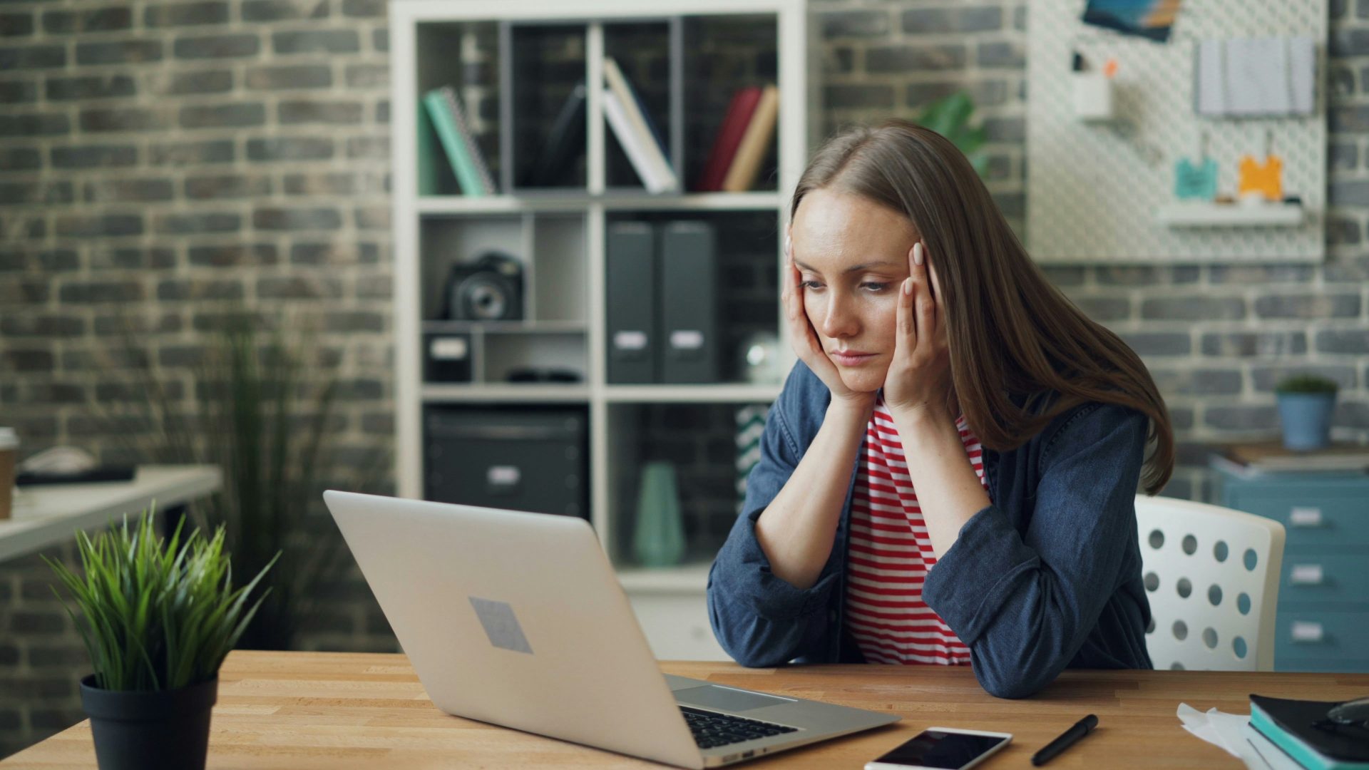 Eine Frau sitzt an einem Tisch, vor ihr ein Laptop.